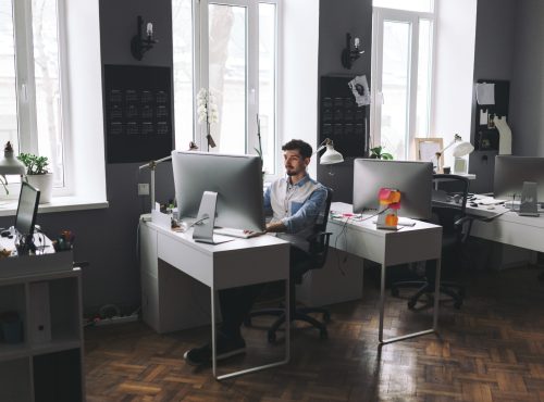 Young man working on computer while sitting at his working place in office